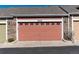 View of the two car garage with stone accents and light fixtures in this townhome at 22725 E Ottawa Pl, Aurora, CO 80016