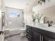 A bathroom featuring a tub with a shower, marble-tiled walls, and a modern vanity with black hardware at 4 Greenridge Rd, Greenwood Village, CO 80111