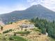 Scenic aerial view of a home nestled on a hillside with mountain backdrop and mature trees at 18844 Ute Vista Trl, Morrison, CO 80465