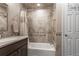 Well-lit bathroom featuring tiled walls, a bathtub with shower, a mirrored vanity, and stylish fixtures at 18844 Ute Vista Trl, Morrison, CO 80465