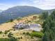 Exterior shot of a home featuring mountain views, a large driveway, and lush surrounding trees at 18844 Ute Vista Trl, Morrison, CO 80465