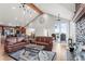 Open living space featuring leather seating, vaulted ceiling, fireplace, and views of the landscape through large windows at 18844 Ute Vista Trl, Morrison, CO 80465