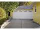 Exterior view of a two-car garage with white door and adjacent yellow siding at 3126 S Vine St, Englewood, CO 80113