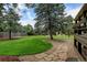 Landscaped backyard with stone path and mature trees at 14121 Countryhills Dr, Brighton, CO 80601