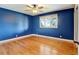 Blue bedroom with hardwood floors and a large window at 14121 Countryhills Dr, Brighton, CO 80601