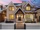 Charming two-story home with a brick facade, black trim windows, a front porch swing, and a wrought iron fence at 2218 S Clayton St, Denver, CO 80210