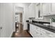 Hallway wet bar featuring a built-in wine fridge, sink, white cabinetry, and elegant countertops at 2218 S Clayton St, Denver, CO 80210