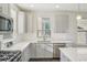 Bright kitchen features stainless steel appliances, gray cabinets and quartz countertops at 5668 Galena St, Denver, CO 80238