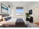 This staged main bedroom features a large window, TV, and soft, comfortable decor at 5668 Galena St, Denver, CO 80238