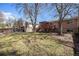 Wide shot of the backyard with a deck, storage shed, and mature trees on a sunny day at 1529 Ashcroft Dr, Longmont, CO 80501