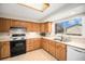 Bright kitchen with wooden cabinets, white appliances, and a large window providing ample natural light at 1529 Ashcroft Dr, Longmont, CO 80501