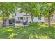 Expansive backyard with mature trees, string lights, and patio furniture for outdoor enjoyment at 9492 Crestmore Way, Highlands Ranch, CO 80126