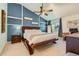 Bedroom featuring vaulted ceiling, a modern ceiling fan, stylish blue accent wall with white shelving and a decorative wooden bed frame at 9492 Crestmore Way, Highlands Ranch, CO 80126