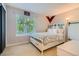 Bright bedroom featuring a floral comforter on the bed, a large sunny window, and a white storage cabinet at 9492 Crestmore Way, Highlands Ranch, CO 80126