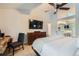 Cozy bedroom featuring large TV, dresser, neutral carpet, and access to an en-suite bathroom with a modern vanity at 9492 Crestmore Way, Highlands Ranch, CO 80126