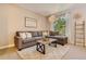 Bright living room with a comfortable gray sectional sofa, throw pillows, a wood coffee table, and natural light from the window at 9492 Crestmore Way, Highlands Ranch, CO 80126