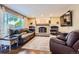 Cozy living room with a brick fireplace, comfortable leather seating, and a large window at 9492 Crestmore Way, Highlands Ranch, CO 80126