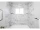 Stylish bathroom tub with a shower, gray marble tiles, and inset shelving at 8511 Cherry Ln, Westminster, CO 80031