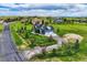 Aerial view of a blue home with a detached garage, surrounded by lush green lawns and mature trees at 41975 Muirfield Loop, Elizabeth, CO 80107