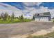 Detached blue garage with multiple bays, long driveway, and verdant trees in the yard at 41975 Muirfield Loop, Elizabeth, CO 80107