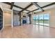 Bright living room boasts stone fireplace, dark wood beams, and a wall of windows to the outside at 41975 Muirfield Loop, Elizabeth, CO 80107
