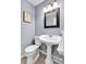 Charming powder room featuring a pedestal sink, framed mirror, and elegant light fixture at 7877 S Ulster St, Centennial, CO 80112