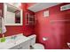Bright bathroom with clean white fixtures, red walls, and a decorative chrome storage rack at 21690 Longs Peak Ln, Parker, CO 80138