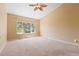 Cozy bedroom featuring carpet floors, light-colored walls, a ceiling fan and a large window with bright outdoor views at 21690 Longs Peak Ln, Parker, CO 80138
