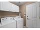 Bright laundry room with white cabinets, washer, dryer, and entry door at 21690 Longs Peak Ln, Parker, CO 80138