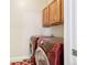 Bright laundry room with upper wood cabinets and modern, red washer and dryer units at 12638 James Pt, Broomfield, CO 80020