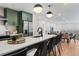 Modern kitchen featuring a large island, matte green cabinets, stainless steel appliances, and modern lighting at 3275 Lawrence St, Denver, CO 80205
