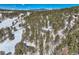 Distant view of a peaceful home nestled in a forest of trees with snow-capped mountains at 21191 Pleasant Park Rd, Conifer, CO 80433