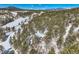 Stunning aerial view of mountain home surrounded by a snow covered evergreen forest and mountain backdrop at 21191 Pleasant Park Rd, Conifer, CO 80433