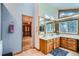 Bathroom featuring wood cabinets, double sinks, and a window with views of the surrounding trees at 21191 Pleasant Park Rd, Conifer, CO 80433