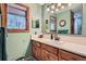 Bathroom with wood cabinet vanity, marble counter top, and window with forested landscape views at 21191 Pleasant Park Rd, Conifer, CO 80433