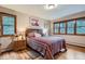 Bedroom with wood floors, a large bed, and dual windows with views of the surrounding trees at 21191 Pleasant Park Rd, Conifer, CO 80433
