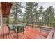 Red deck with outdoor furniture set with bench seating and views of the trees at 21191 Pleasant Park Rd, Conifer, CO 80433