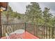 Red wooden deck with a table and chairs featuring metal railings overlooking the forest at 21191 Pleasant Park Rd, Conifer, CO 80433