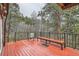 Red deck area with black railings, bench, and chair with views of the surrounding forest at 21191 Pleasant Park Rd, Conifer, CO 80433