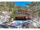 Exterior view of stone-clad home with a three-car garage and a spacious outdoor deck at 21191 Pleasant Park Rd, Conifer, CO 80433