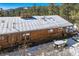 Cozy wood-sided home with a snowy roof, skylights, a stone chimney, and an outdoor deck at 21191 Pleasant Park Rd, Conifer, CO 80433
