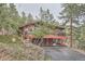 Elevated rustic home with wooden deck, garage, and stone retaining walls at 21191 Pleasant Park Rd, Conifer, CO 80433