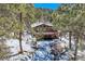 Stone-clad home nestled in a wooded area with a deck and snowy landscape at 21191 Pleasant Park Rd, Conifer, CO 80433