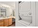 Bathroom vanity with sink and wood cabinets next to a stacked washer and dryer at 9222 E Arbor Cir # L, Englewood, CO 80111