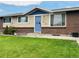 Charming single-story home with a brick and siding exterior, complemented by a well-manicured lawn and a cheerful blue front door at 5690 W 79Th Ave, Arvada, CO 80003