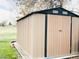 Tan-colored storage shed with a door, air vents, and black trim, on a well-maintained lawn at 5690 W 79Th Ave, Arvada, CO 80003