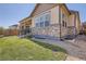 Exterior side view of home with backyard lawn, stone accents, and a covered patio at 25561 E 5Th Pl, Aurora, CO 80018