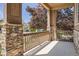 Covered front porch framed with stone columns and wooden railing providing a relaxing outdoor space at 25561 E 5Th Pl, Aurora, CO 80018