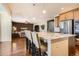 Bright kitchen with granite island, seating, stainless appliances and hardwood floors leading to the living room at 25561 E 5Th Pl, Aurora, CO 80018