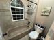 Bathroom with tiled tub, arched window, toilet and wall accessories at 6887 S Dover Way, Littleton, CO 80128